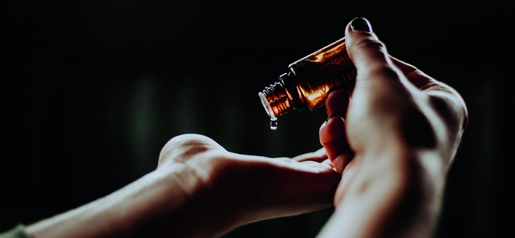 Essential oil dropped into hand from bottle before being used for aromatherapy