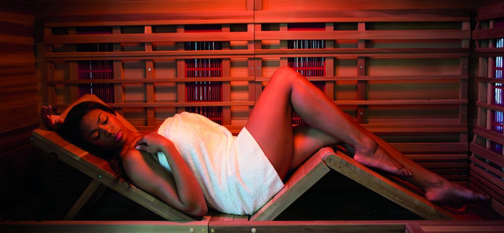 Young woman using the adjustable bench seat to recline in her infrared sauna
