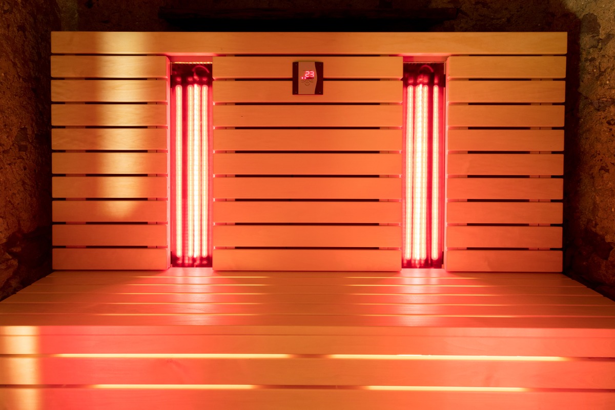 A close-up of the wooden bench of an infrared sauna. The vertical infrared sauna lights are within openings of the bench.